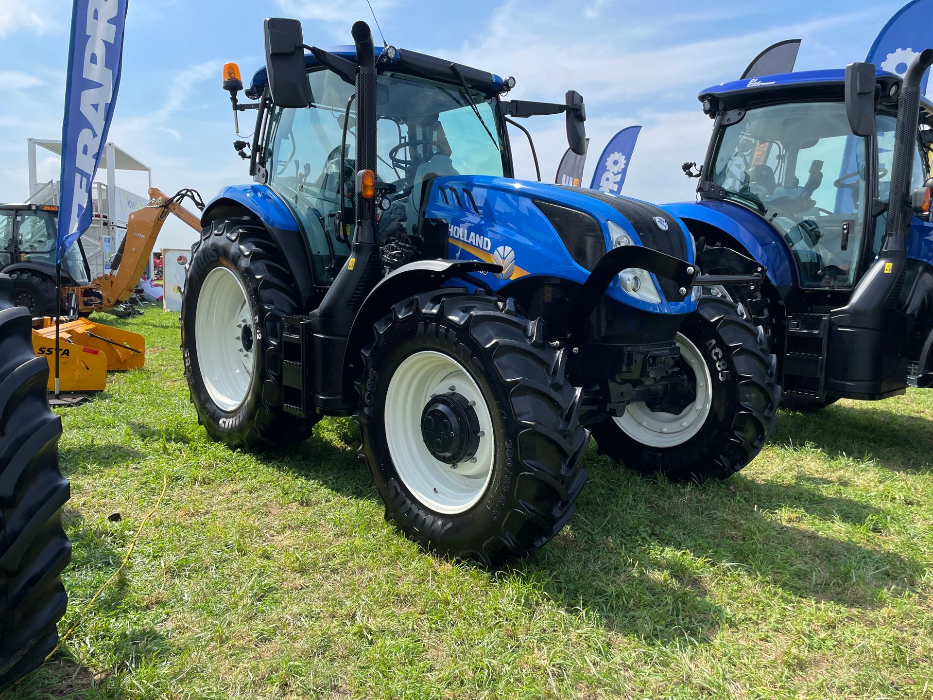 Un tracteur bleu et noir est garé dans un champ herbeux.