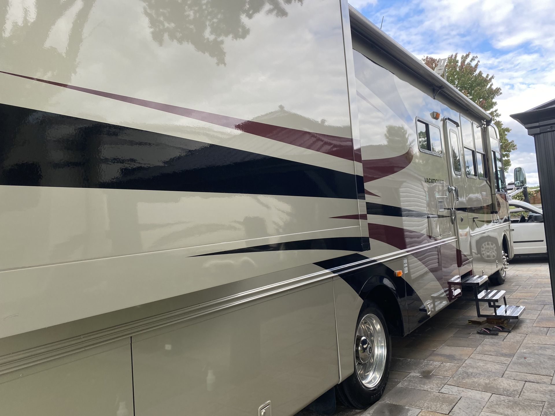 Un grand camping-car blanc et rouge est garé dans une allée.
