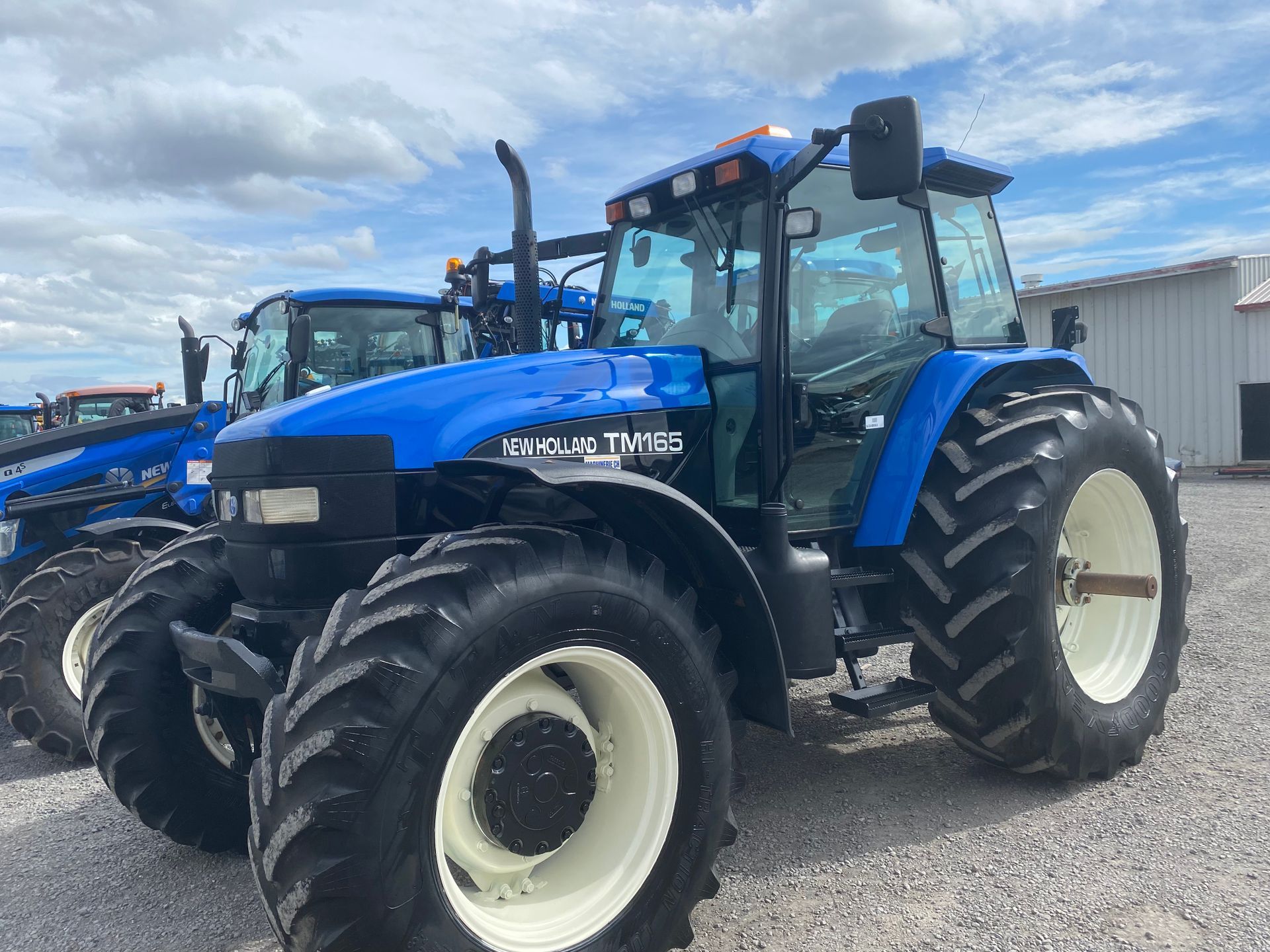 Un tracteur bleu est garé devant un immeuble.