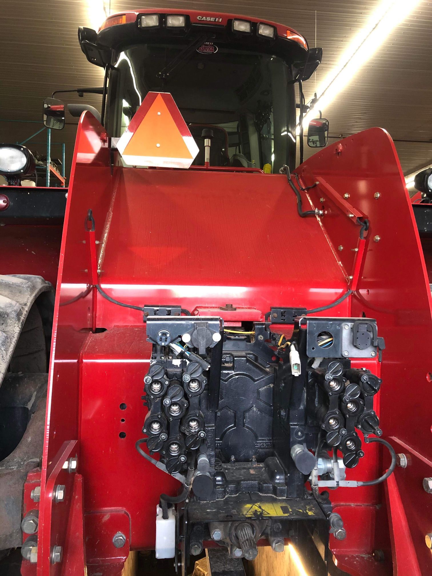 Un tracteur rouge est garé dans un garage avec un triangle sur le devant.