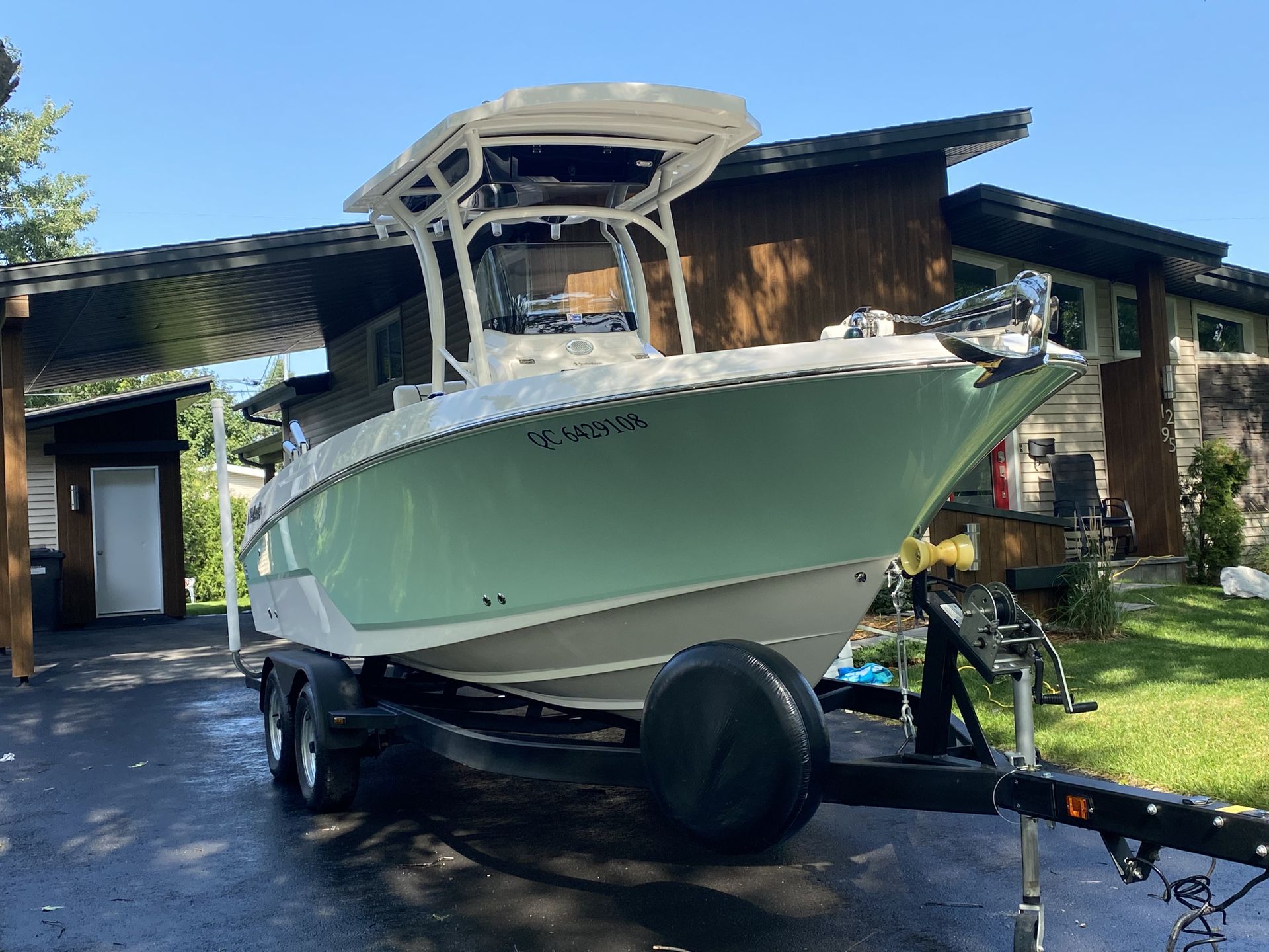 Un bateau est garé sur une remorque devant une maison.
