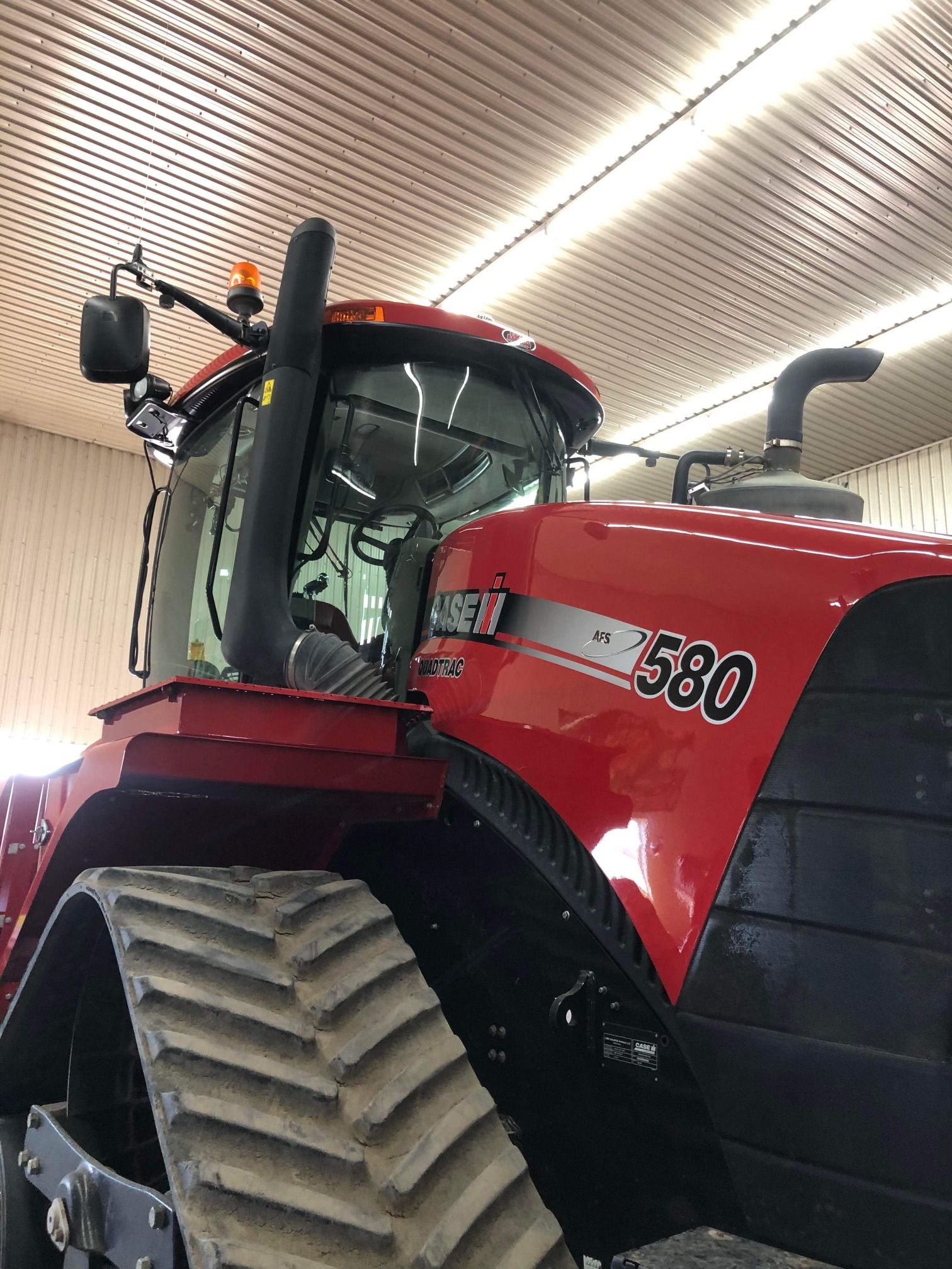 Un tracteur rouge case 580 est garé dans un garage.