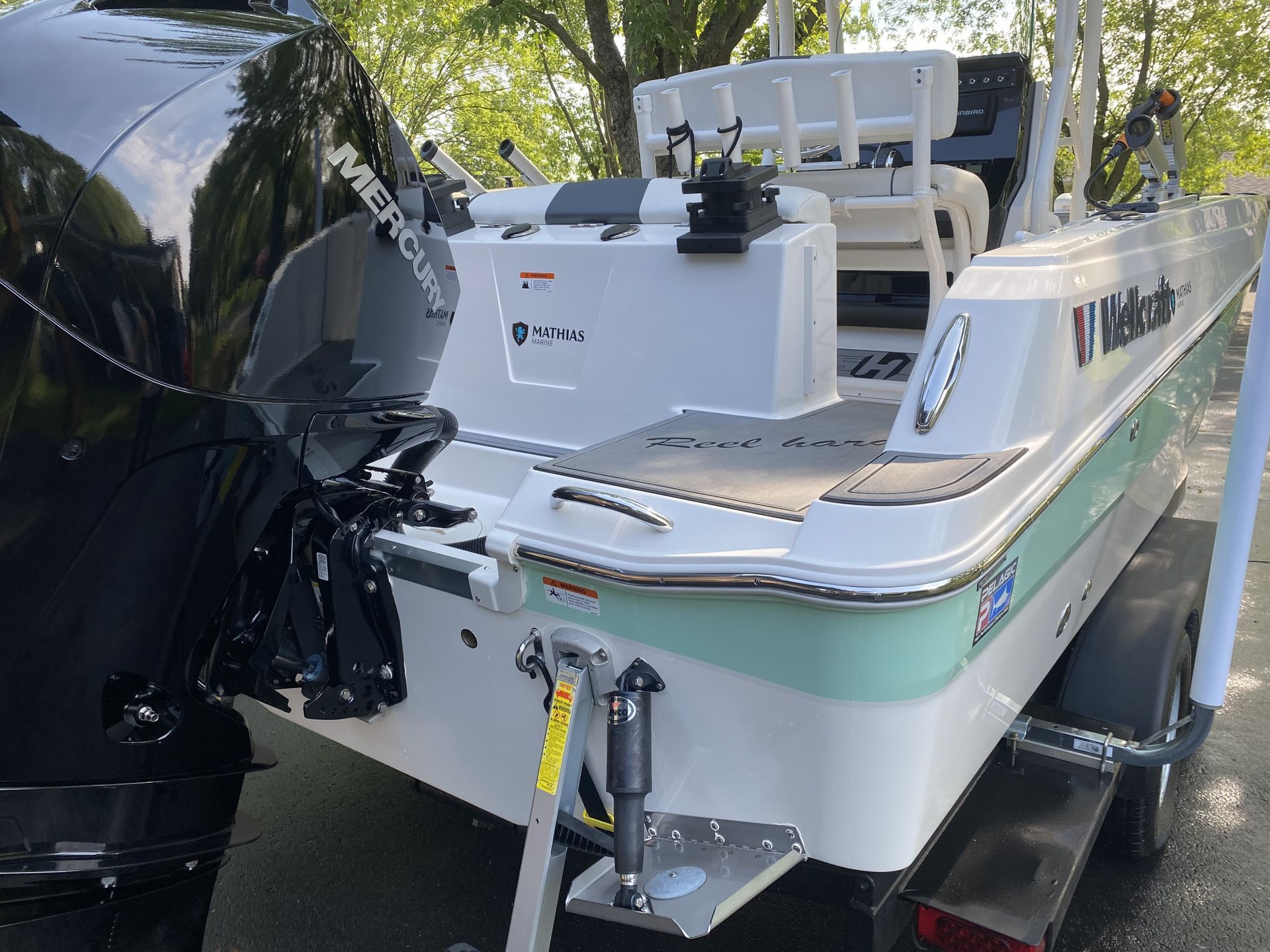 Un bateau est posé sur une remorque à laquelle est attaché un moteur au mercure.