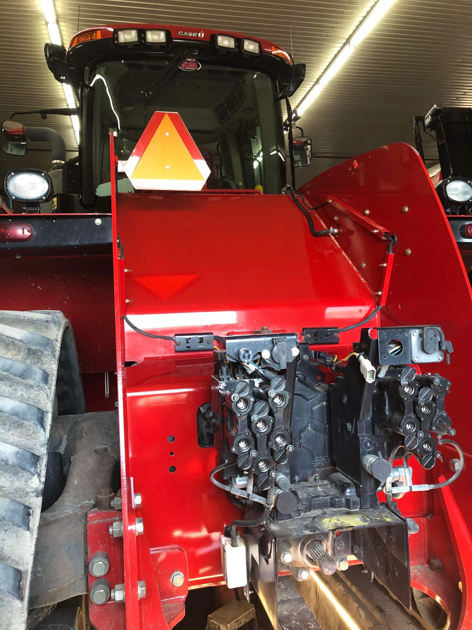 Un tracteur rouge est garé dans un garage avec son capot relevé.