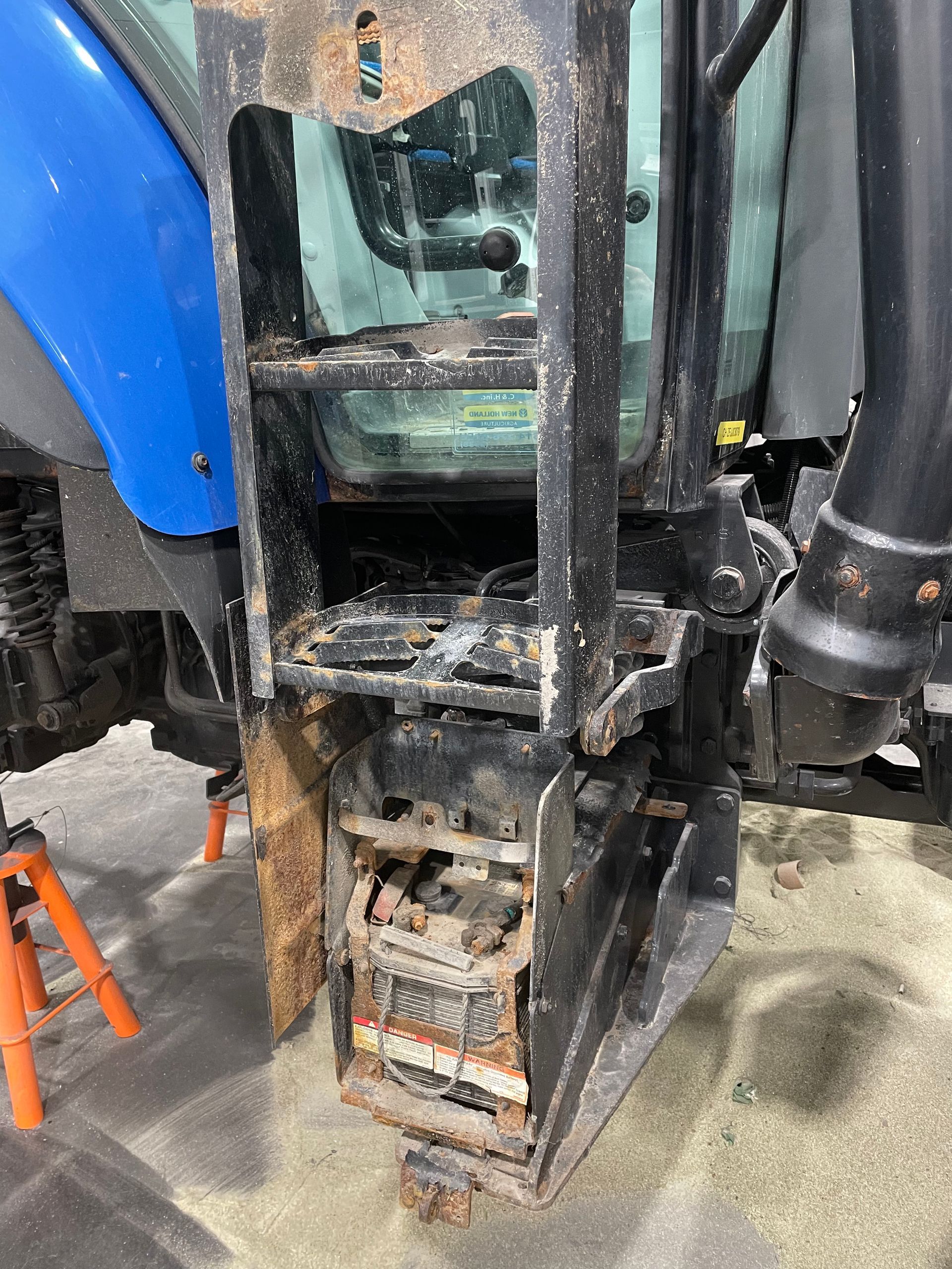 Un tracteur bleu et noir est posé par terre dans un garage.