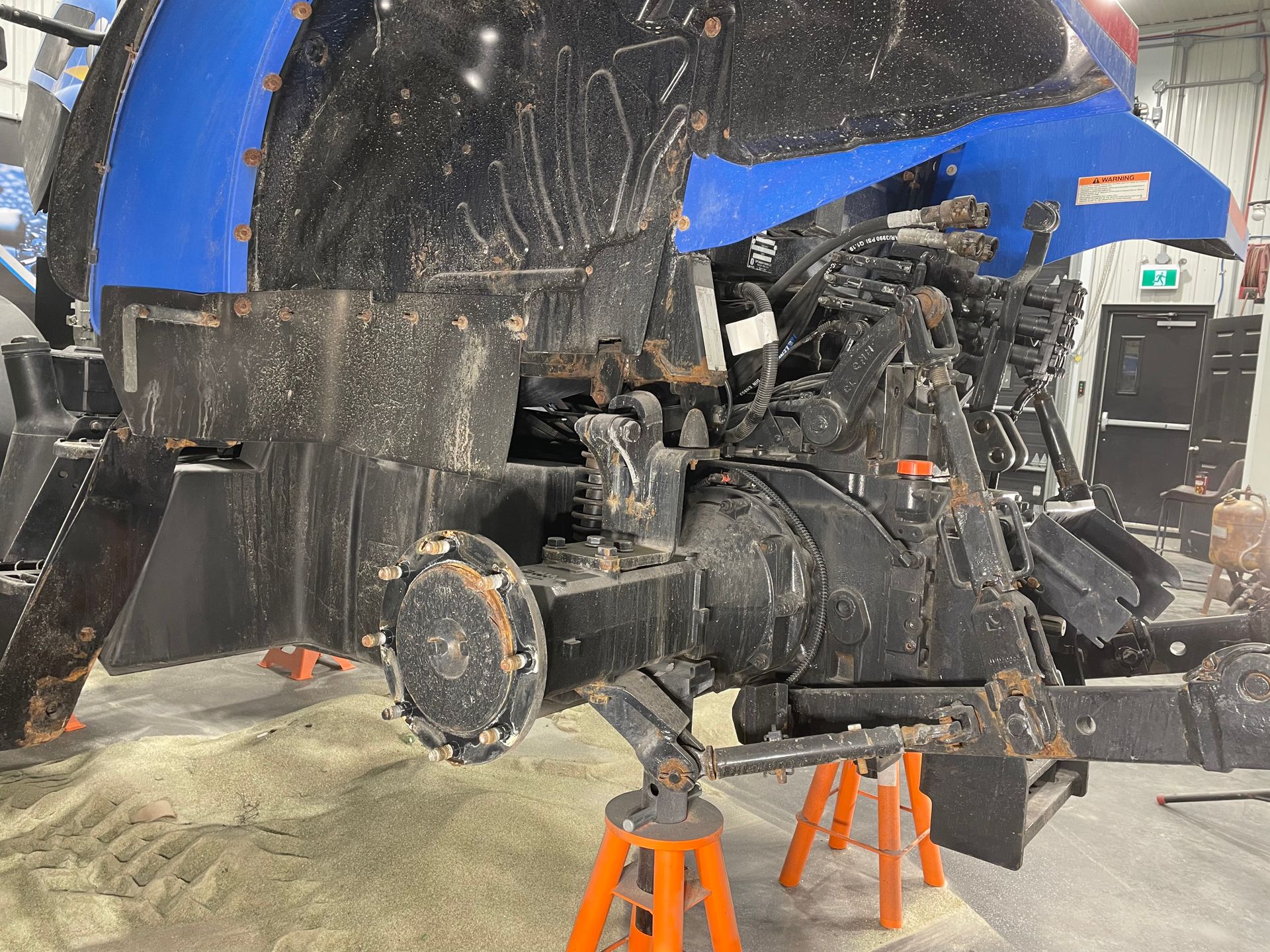 Un tracteur bleu et noir est assis sur des chandelles dans un garage.