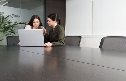 two women talking at computer in conference room