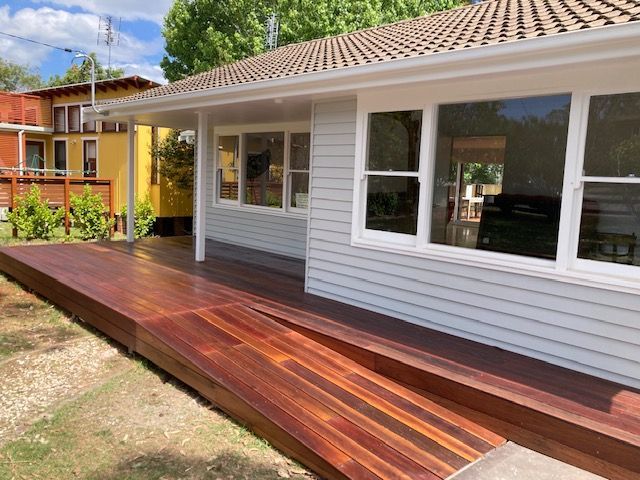 A white house with a wooden deck in front of it. — Brad Griffiths Building In Culburra Beach, NSW