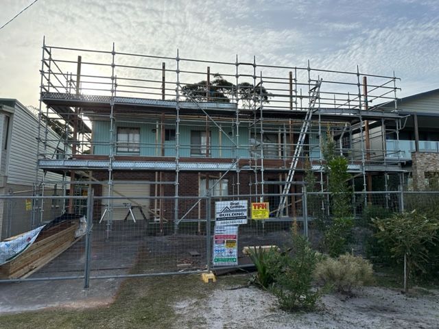 A Man Wearing A Hat Is Working On The Roof Of A Building — Brad Griffiths Building In Culburra Beach, NSW