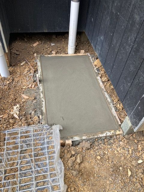 Freshly poured concrete slab within a wooden frame, next to a building and plumbing pipe - Brad Griffiths Building In Culburra Beach, NSW