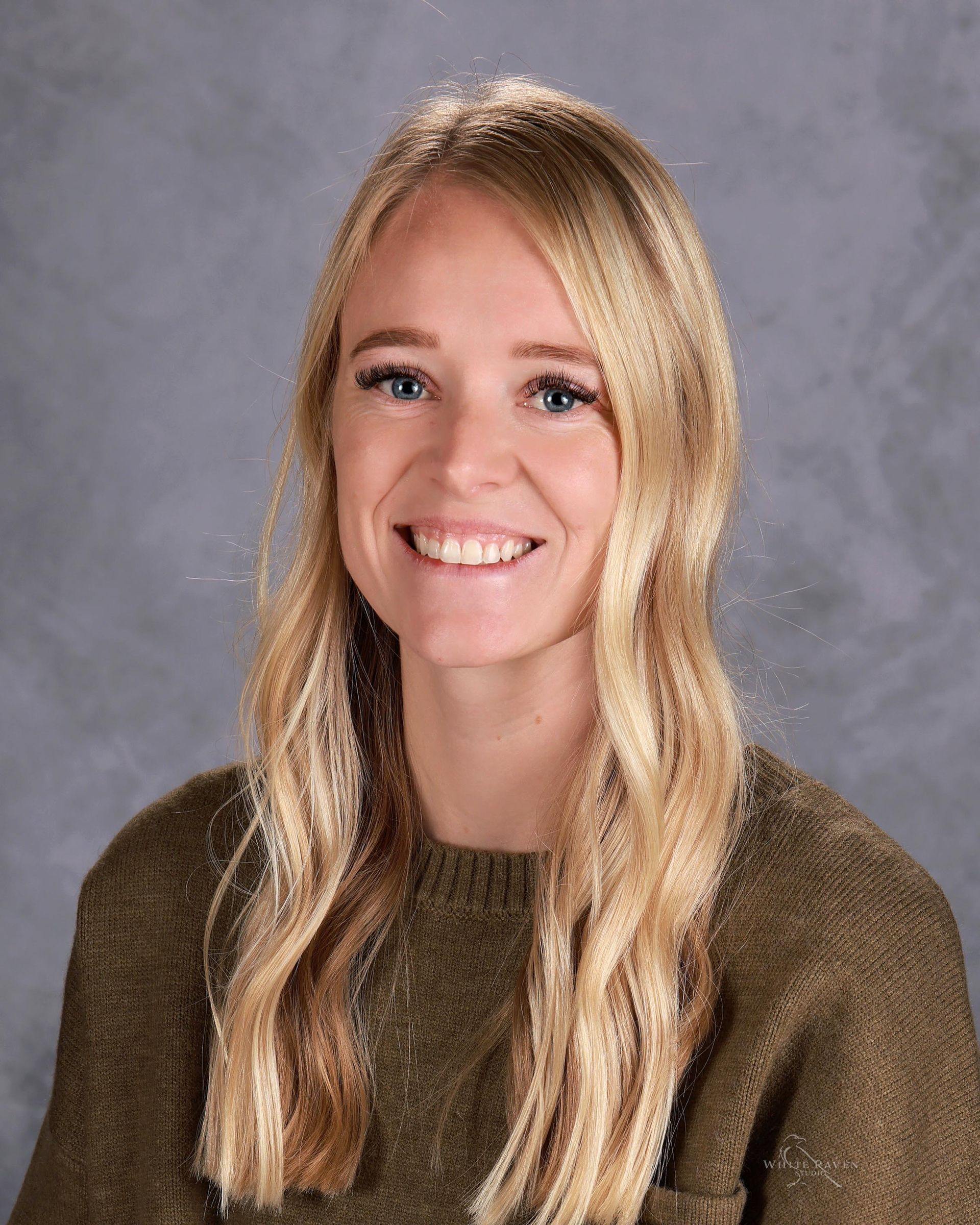 A woman wearing a brown shirt is smiling for the camera.