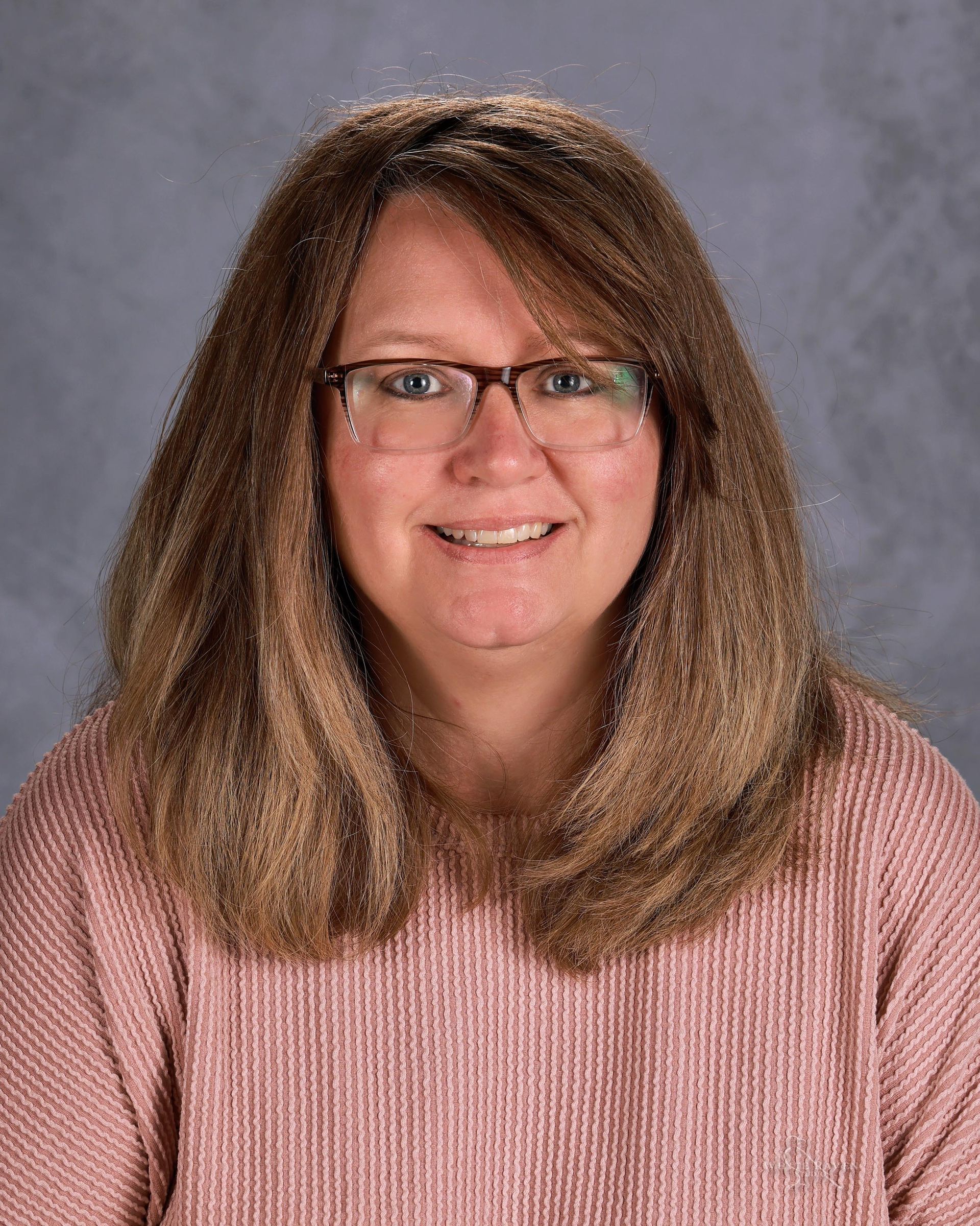 Woman in orange shirt smiling at camera.