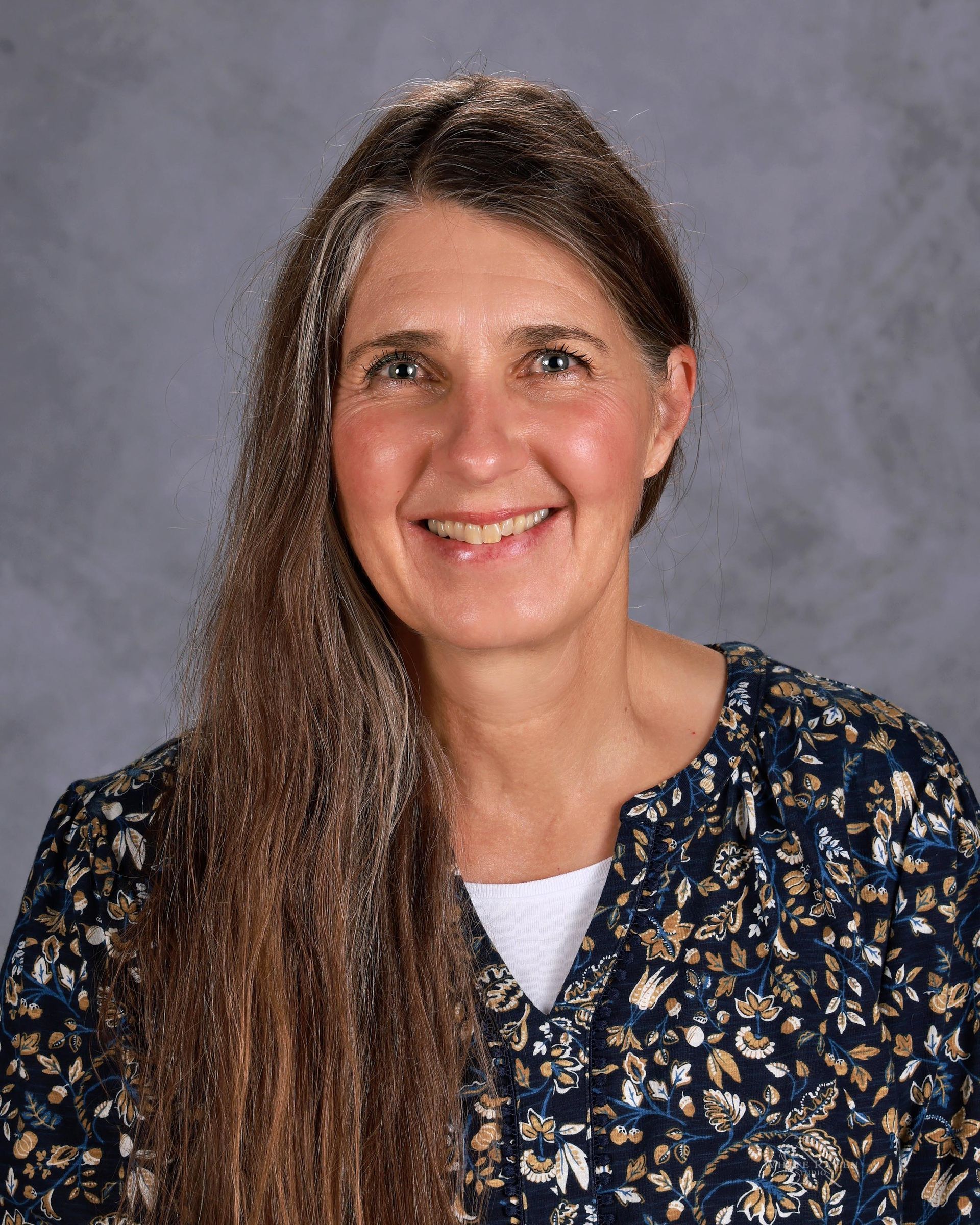 A woman with long hair is smiling for a picture.