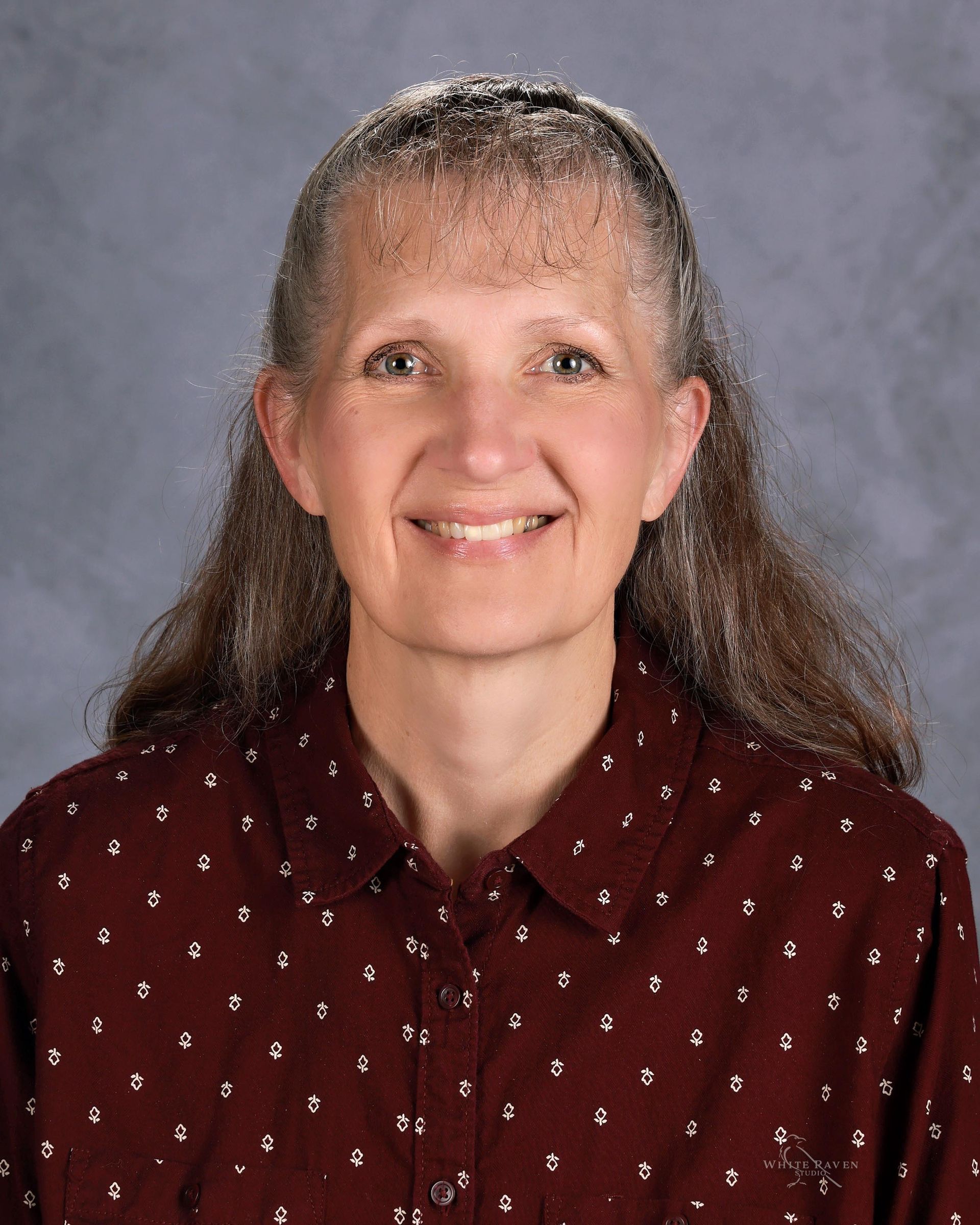 A woman wearing a red shirt with white polka dots is smiling for the camera.
