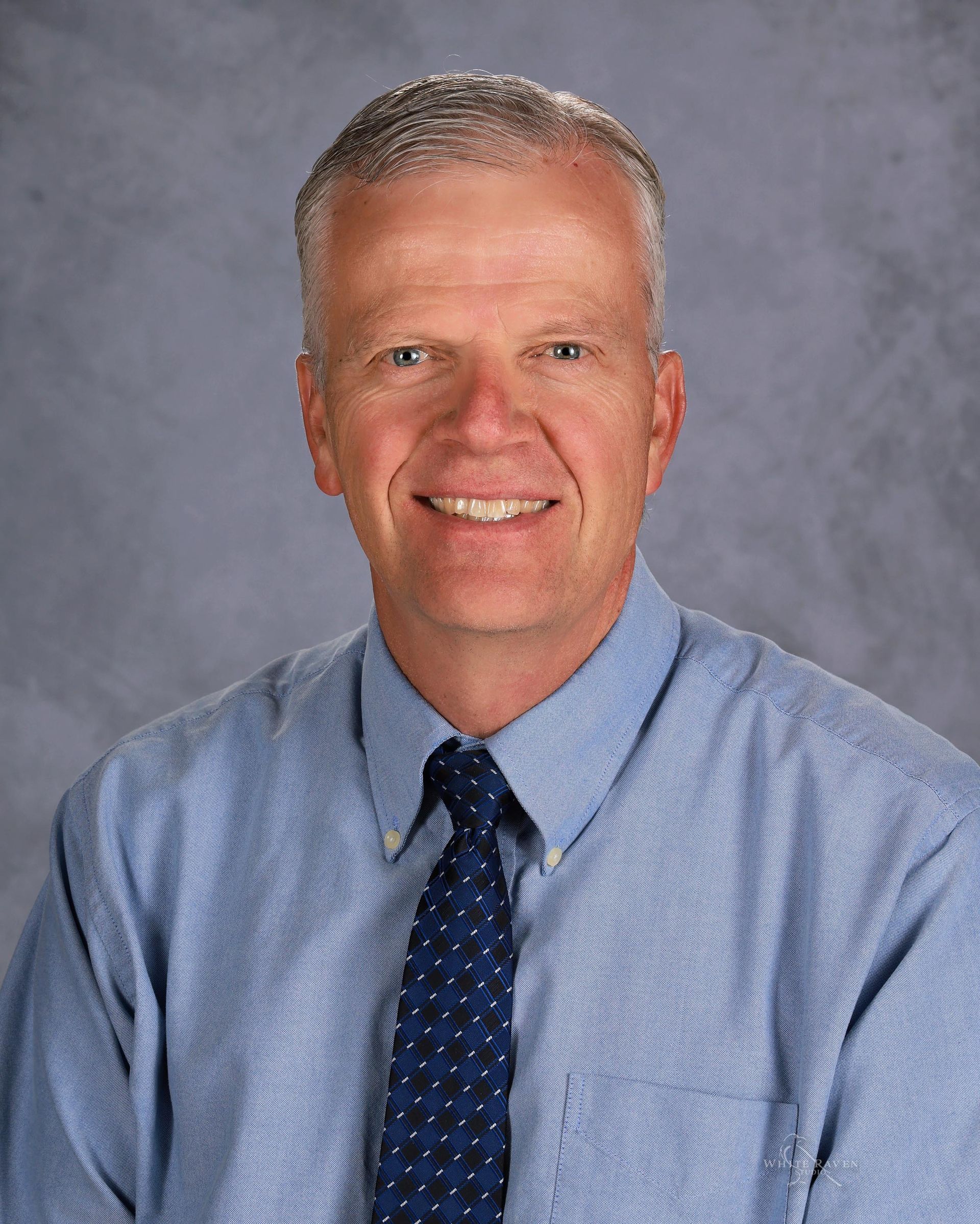 A man in a striped shirt and tie is smiling for the camera.