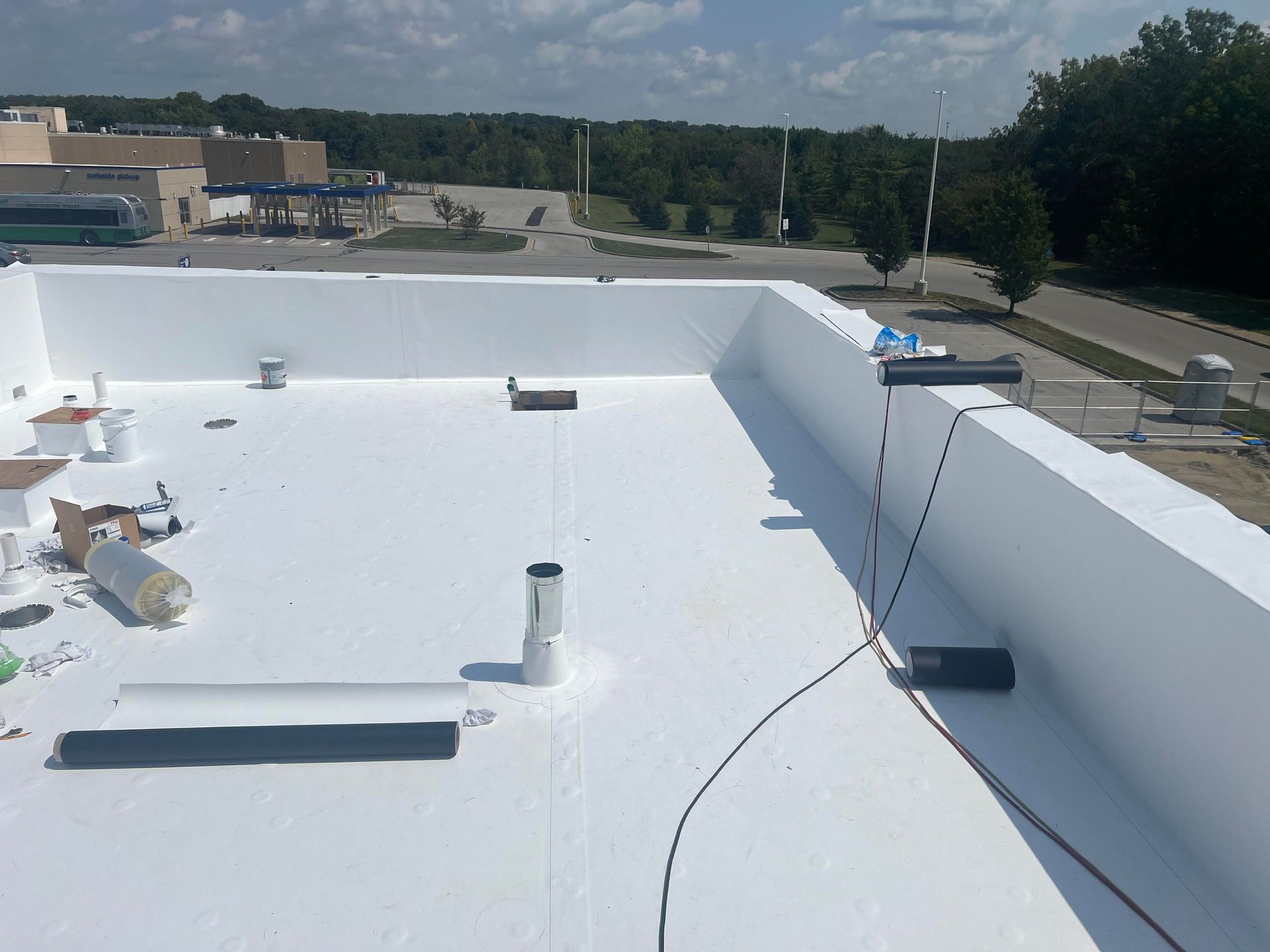 White commercial flat roof with work in progress, building exterior, sunny day.
