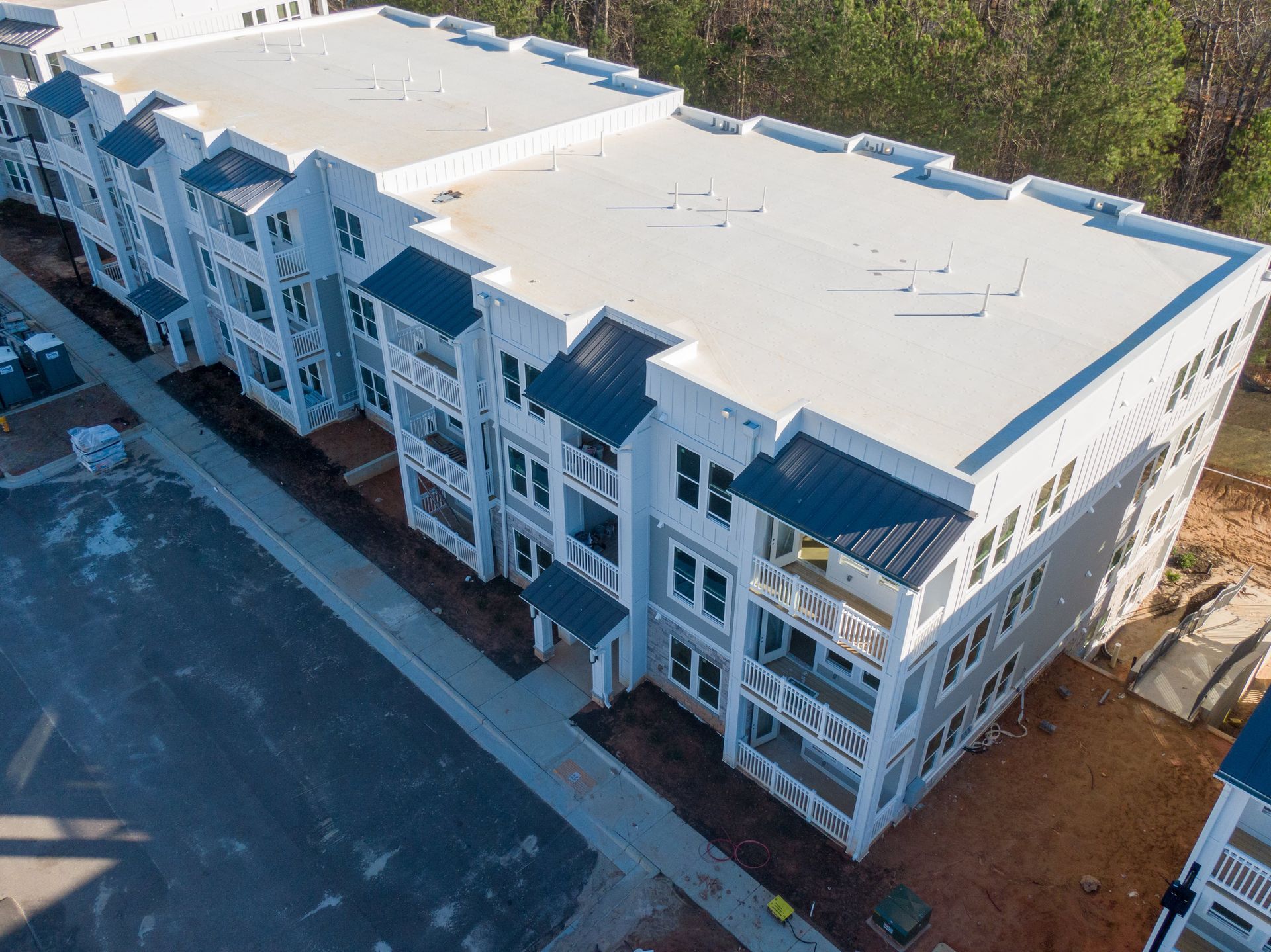 Multi-story apartment building with gray siding, white trim, and dark blue roof accents.
