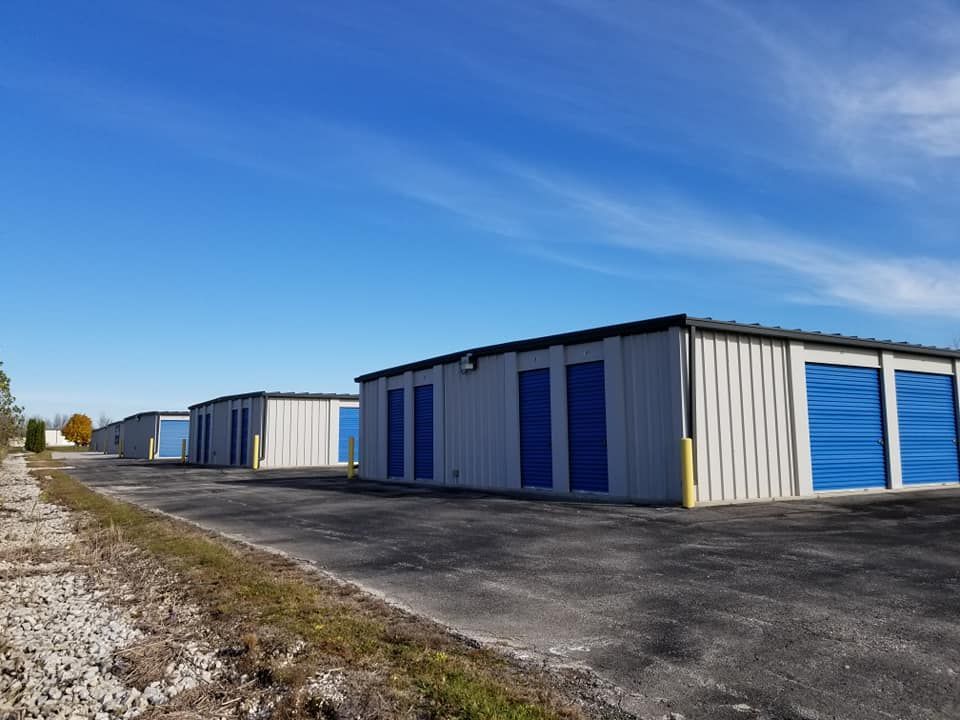 Storage units with blue doors under a bright blue sky.