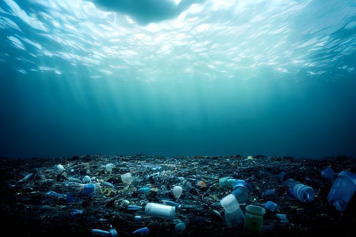 A pile of plastic bottles and cups floating in the ocean.