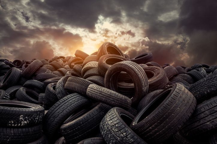 A pile of tires stacked on top of each other with the sun shining through the clouds.