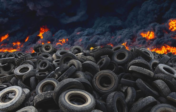 A pile of tires is sitting in front of a fire.