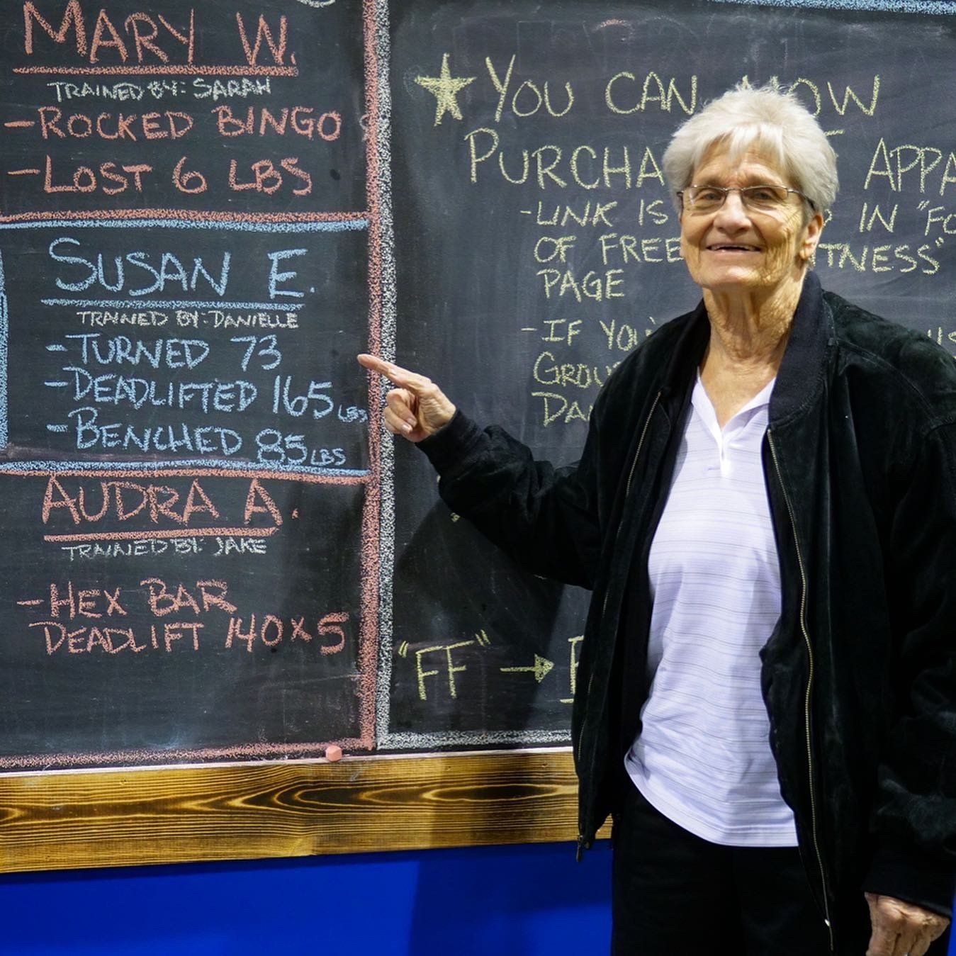 old woman pointing at a board