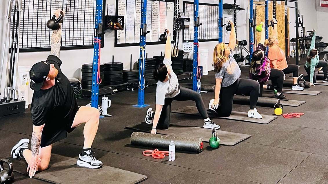 Mobility class of people doing kettlebell half kneeling windmills