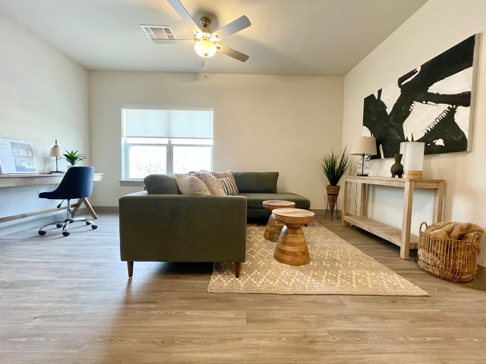 A living room with a couch , desk and a ceiling fan.
