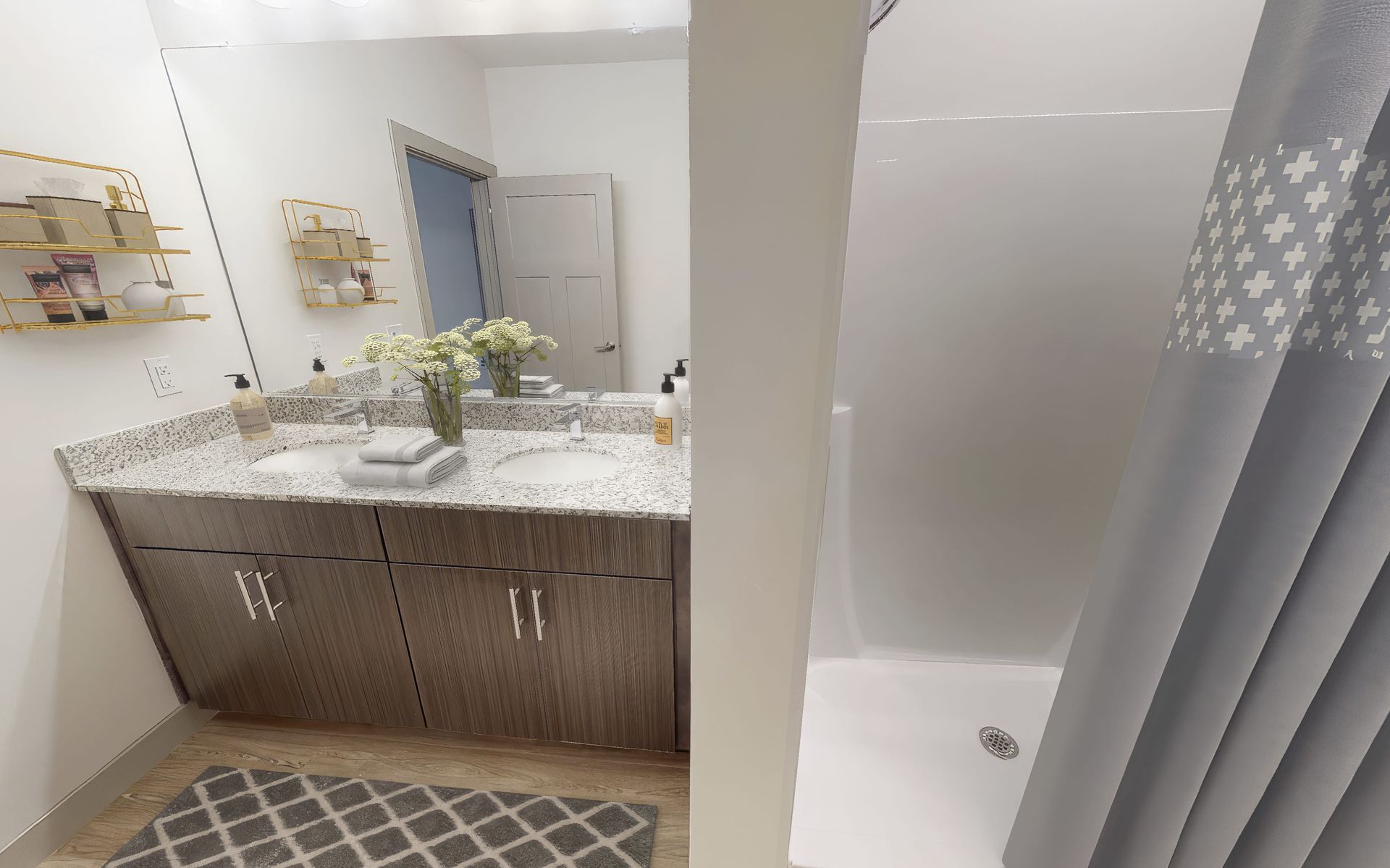 A bathroom with a sink , shower and mirror.