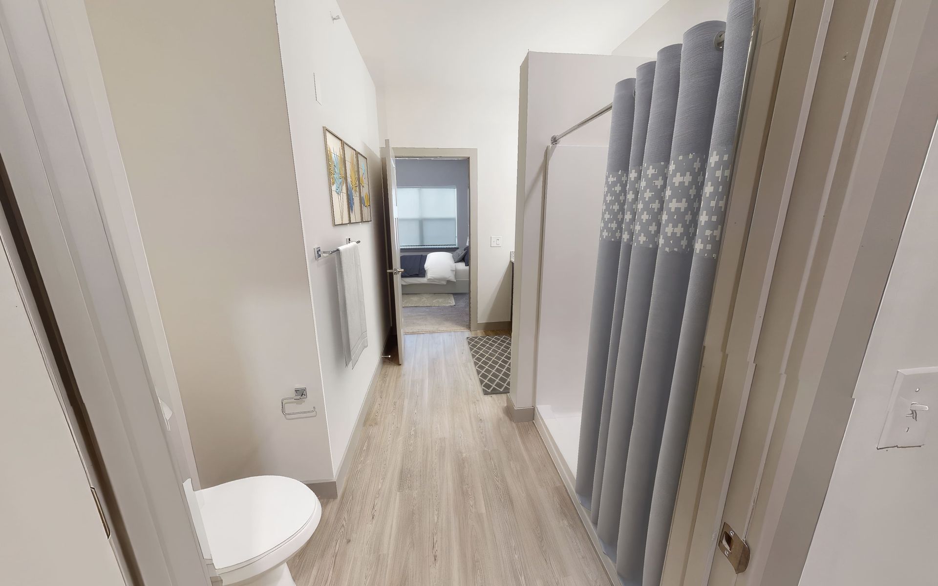 A bathroom with a toilet , shower , and towel rack.