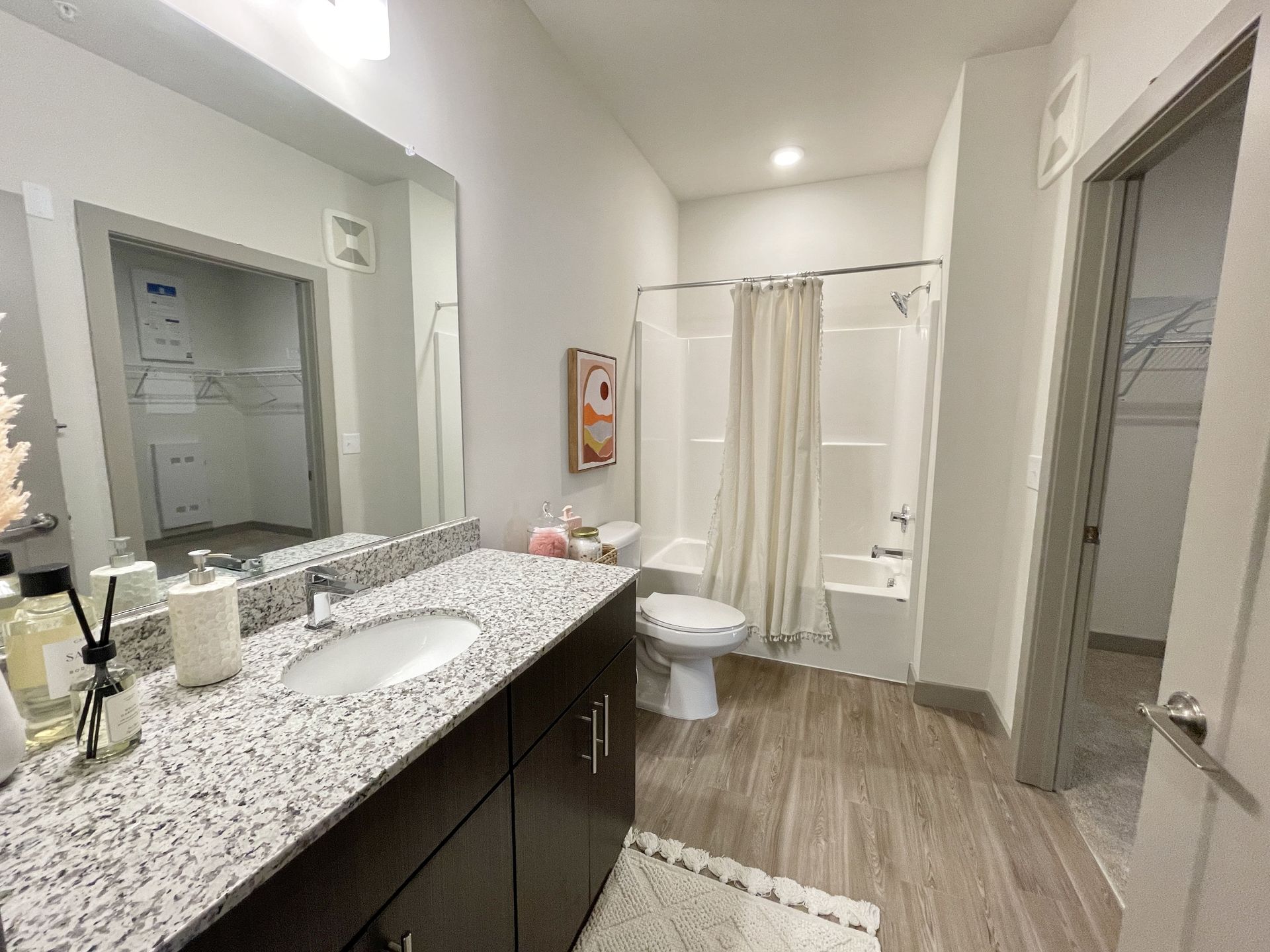 A bathroom with a sink , toilet , shower and mirror.