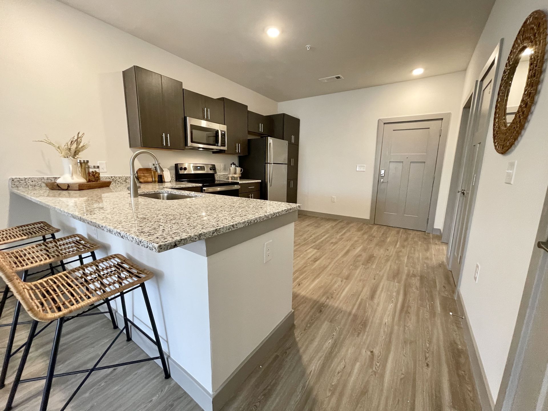 A kitchen with granite counter tops , stainless steel appliances , a refrigerator and a sink.