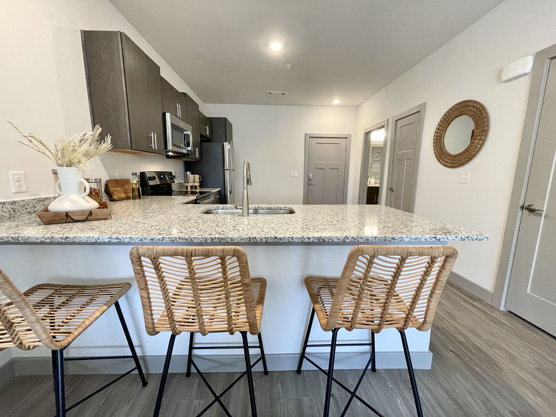 A kitchen with a granite counter top and wicker chairs