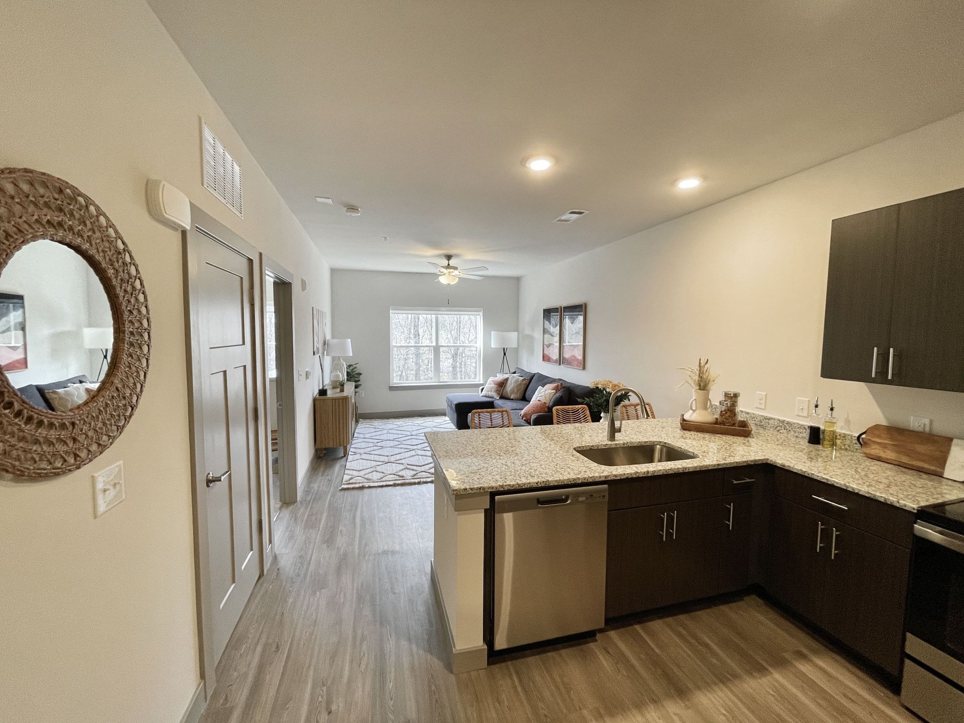 A kitchen with granite counter tops , stainless steel appliances , a sink and a mirror.