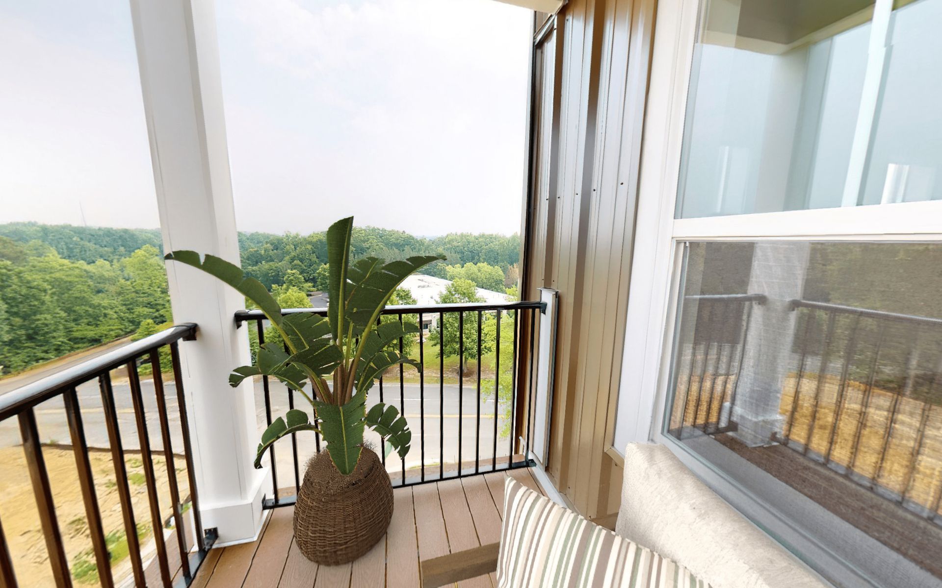 A balcony with a plant on it and a view of the woods.