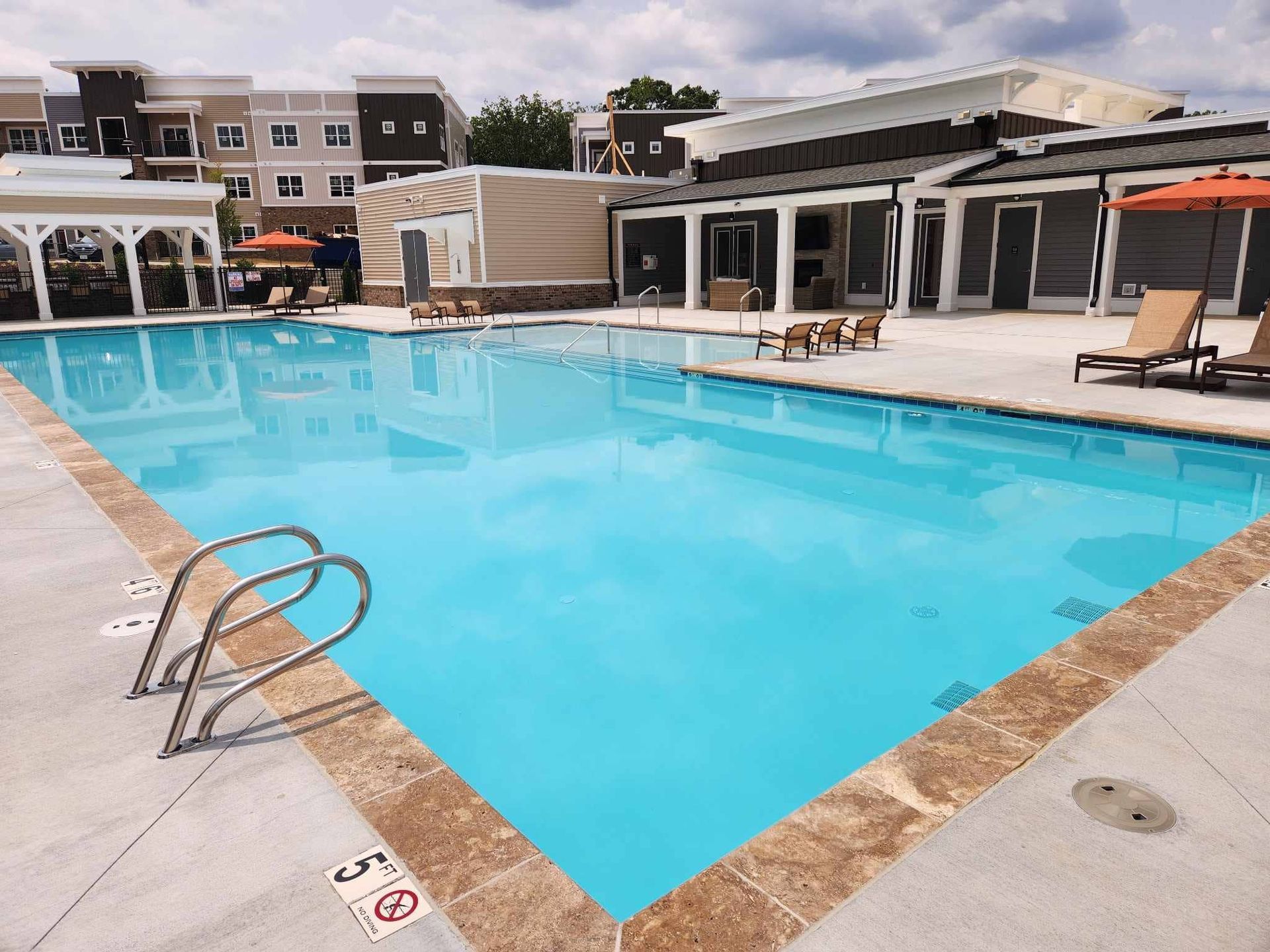 A large swimming pool is surrounded by chairs and umbrellas