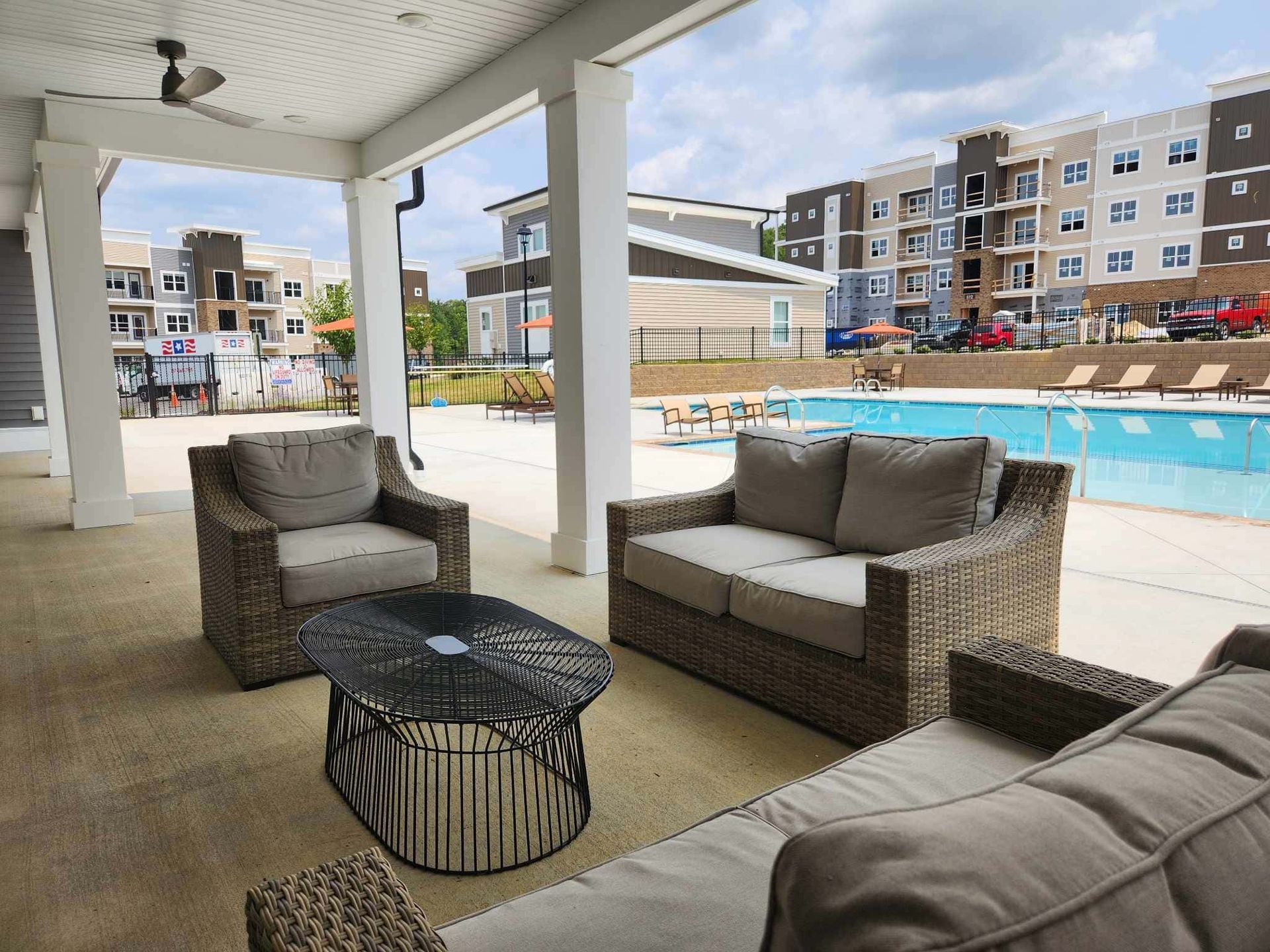 A patio with a couch , chairs and a table next to a pool.