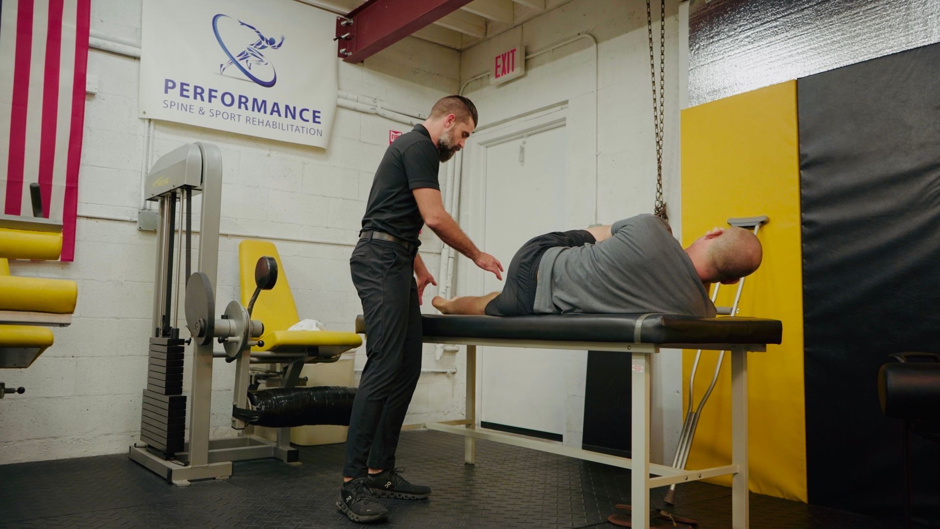 Man with knee pain in a gym, holding his leg with a red highlighted knee.