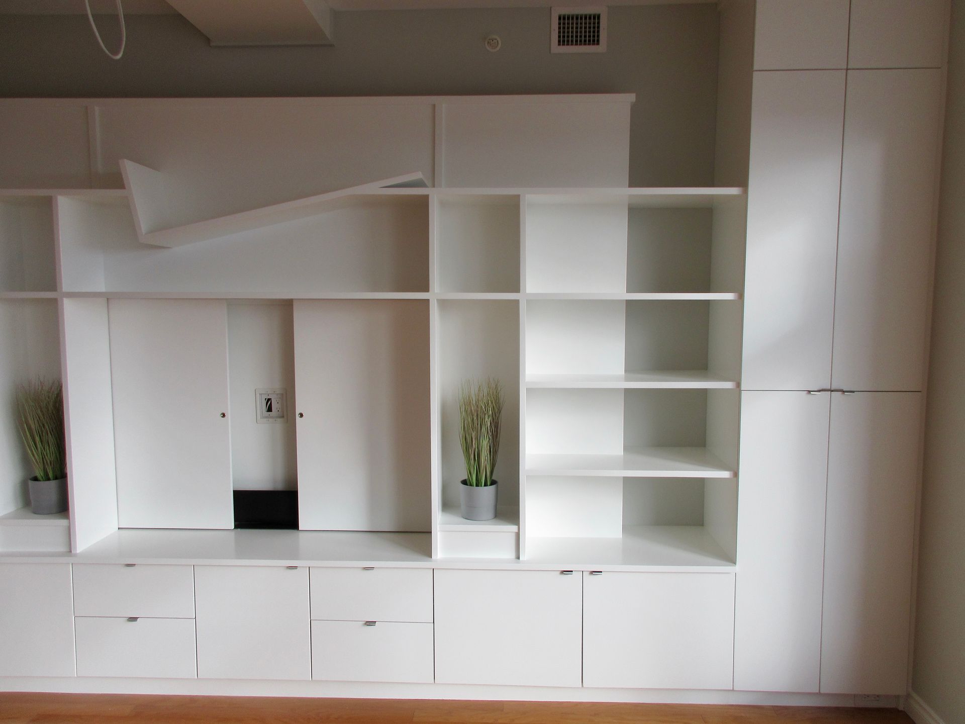 White built-in shelving and cabinets with open and closed sections; includes shelves, doors, and storage.