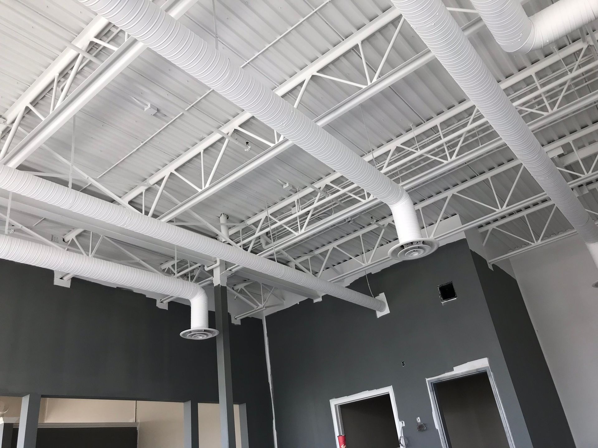 A room with a ceiling that has a lot of pipes hanging from it.