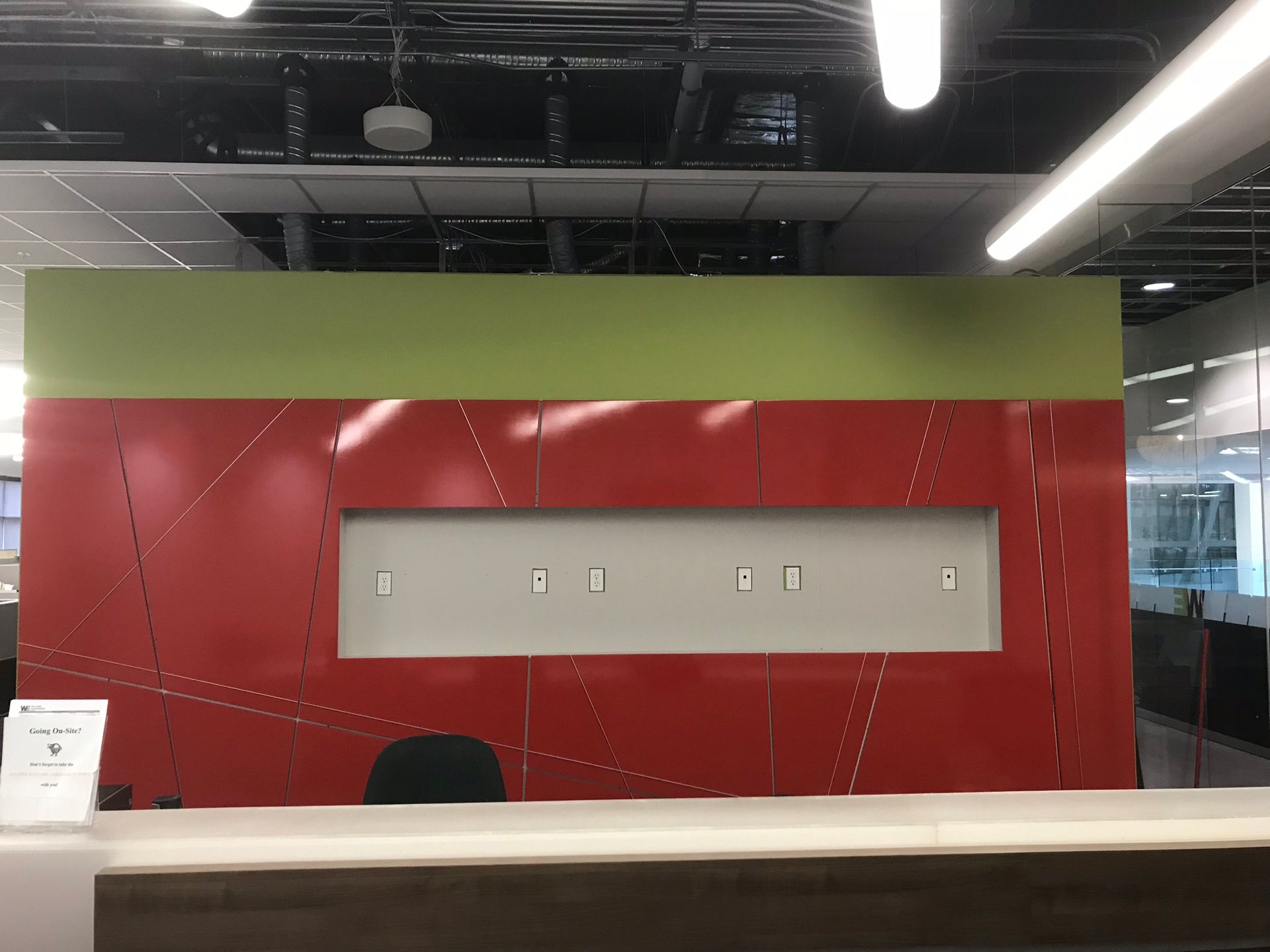 A reception desk in an office with a red wall and a green wall behind it.