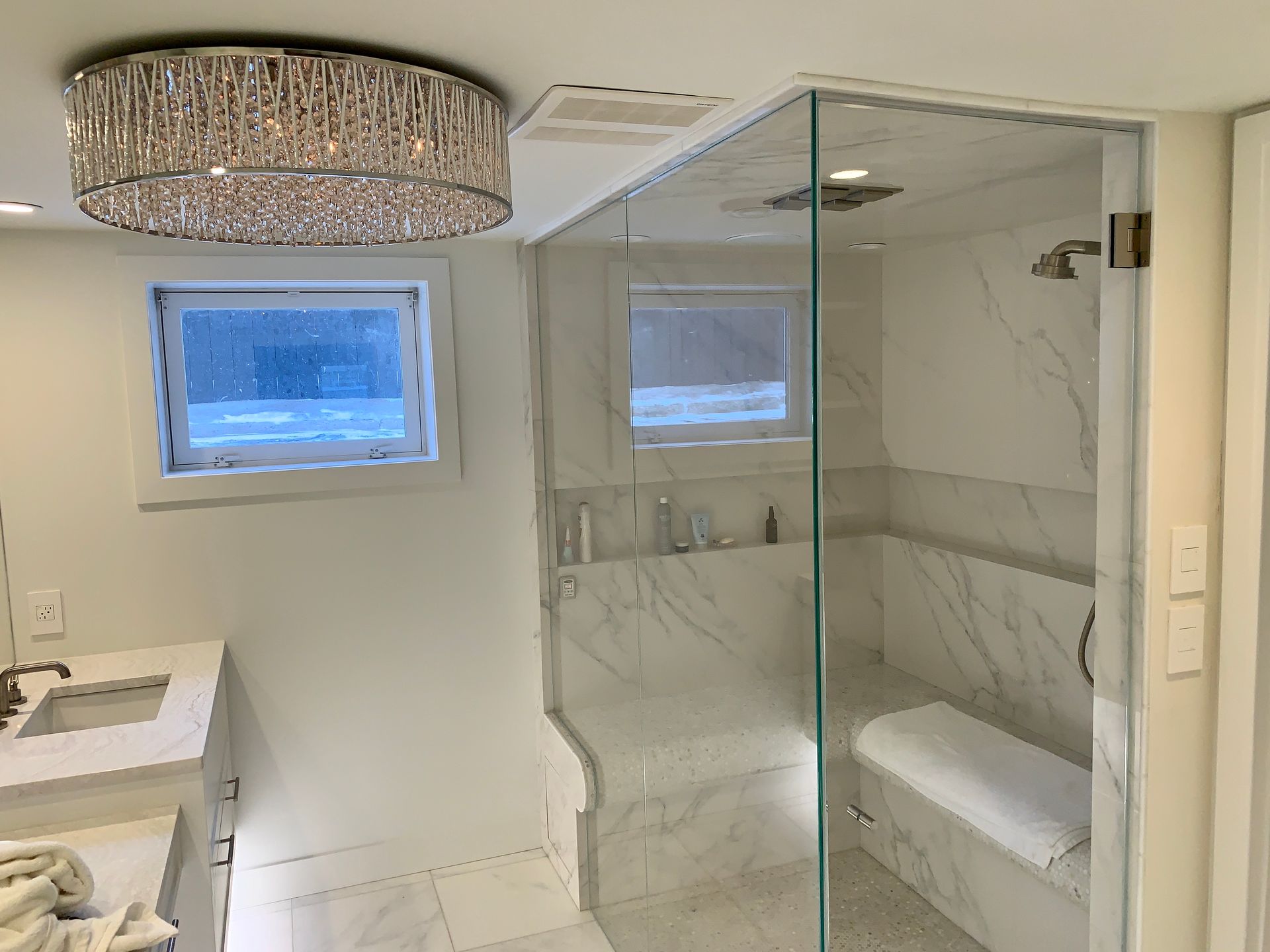 A bathroom with a walk in shower , sink , and window.