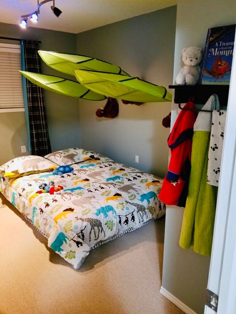 Bedroom with a bed, animal-themed bedding, a decorative airplane, coat rack, and teddy bear.