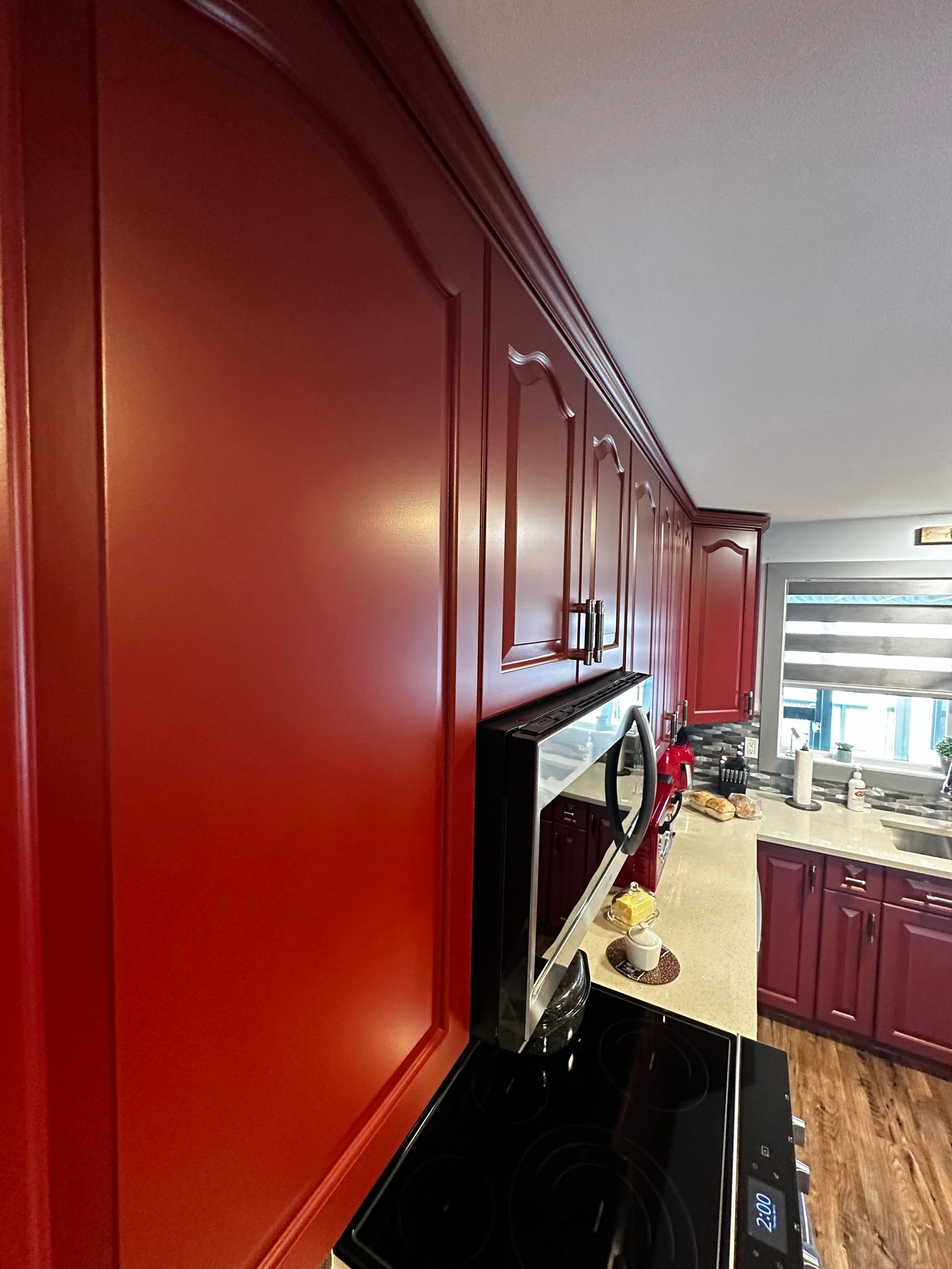 A kitchen with red cabinets and a black stove top oven