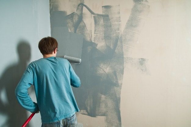 A man is painting a wall with a paint roller.