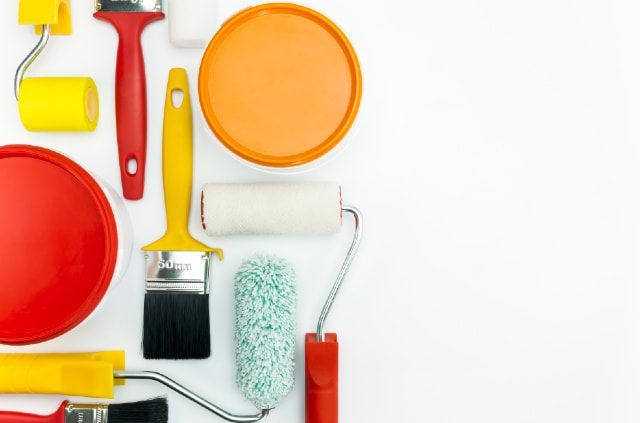 A bunch of paint rollers and brushes on a white surface.