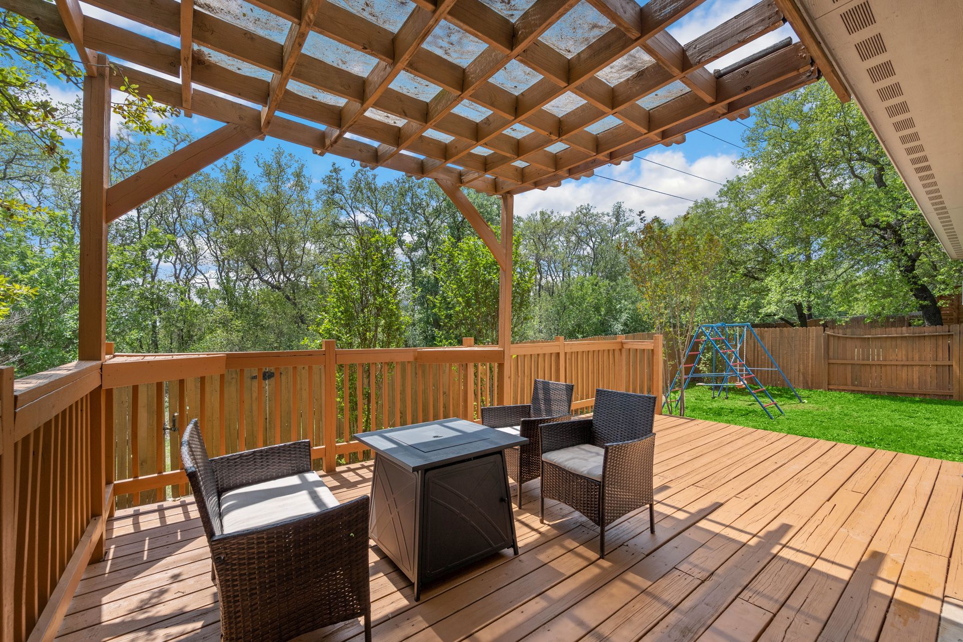 Wooden deck with outdoor furniture, a pergola, and a view of trees and greenery