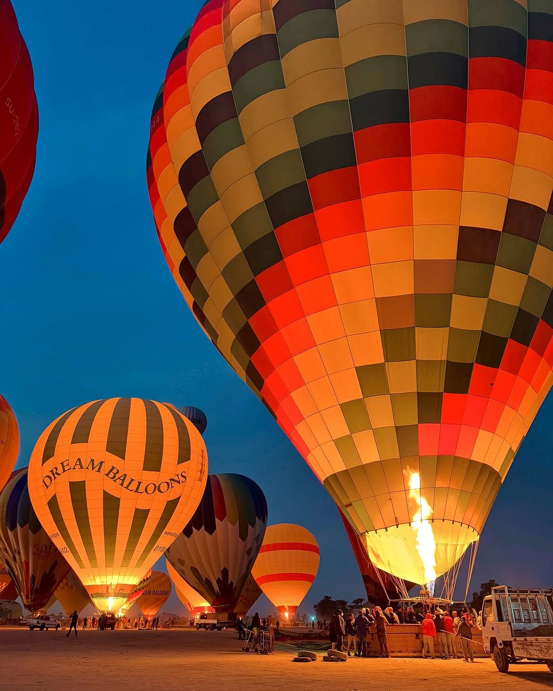 hot air balloons flying over the West Bank mountains and lush green farmlands in Luxor, Egypt at sunrise.