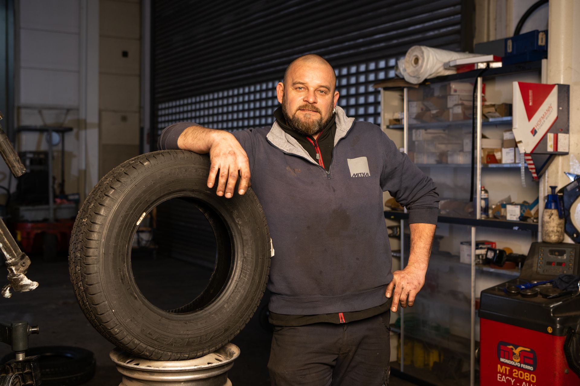 Automechaniker steht neben einem Autoreifen Stapel