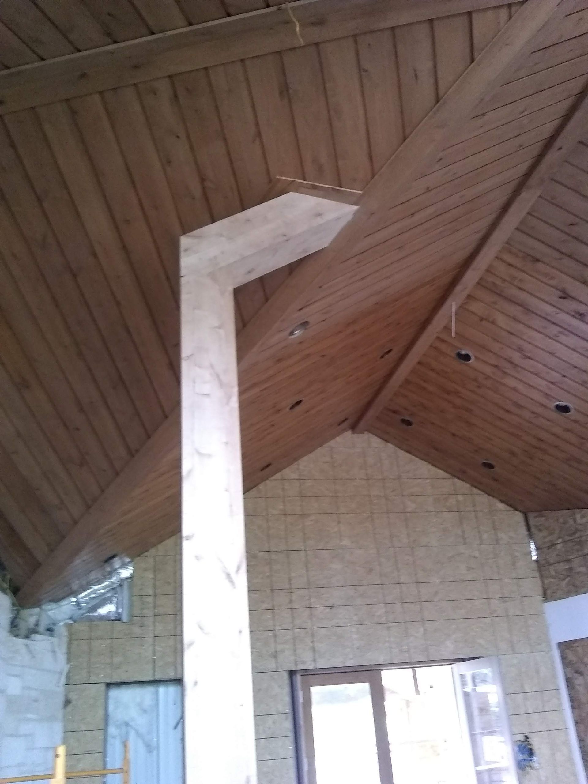 A room with a wooden ceiling and a white column
